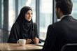 Middle eastern businesswoman wearing a hijab having a meeting conversation with a co-worker at the workplace