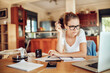 © Geber86 - Young woman going over her financials in the kitchen of her home