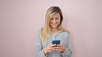 Wall Mural - Young blonde woman smiling confident using smartphone over isolated pink background