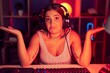 © Krakenimages.com - Young blonde woman playing video games wearing headphones clueless and confused expression with arms and hands raised. doubt concept.