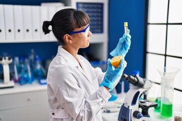 Canvas Print - Young beautiful hispanic woman scientist holding lemon and test tube at laboratory