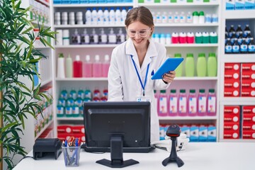 Poster - Young blonde woman pharmacist smiling confident using computer and touchpad at pharmacy