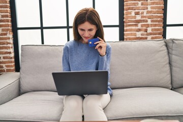 Poster - Young blonde woman shopping with laptop and credit card thinking at home