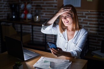 Canvas Print - Young redhead woman working at the office at night stressed and frustrated with hand on head, surprised and angry face