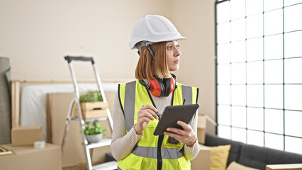 Wall Mural - Young blonde woman architect using touchpad with serious expression at new home