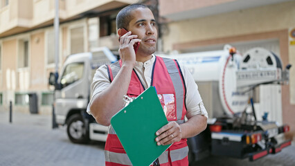 Sticker - Young hispanic man volunteer holding clipboard speaking on the phone at street