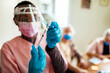 © Marko Geber - Young African American caregiver preparing a vaccine for her patient in their home