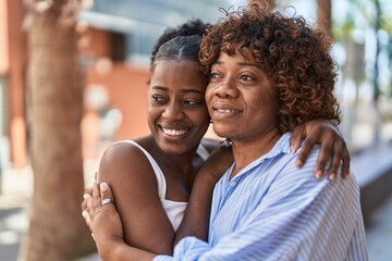 Wall Mural - African american women mother and daughter hugging each other at street