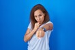 © Krakenimages.com - Brunette woman standing over blue background punching fist to fight, aggressive and angry attack, threat and violence