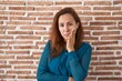 © Krakenimages.com - Brunette woman standing over bricks wall thinking looking tired and bored with depression problems with crossed arms.