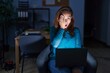 © Krakenimages.com - Brunette woman working at the office at night covering one eye with hand, confident smile on face and surprise emotion.