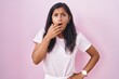 © Krakenimages.com - Young hispanic woman standing over pink background looking fascinated with disbelief, surprise and amazed expression with hands on chin