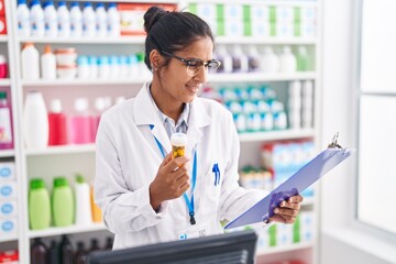 Sticker - Young beautiful hispanic woman pharmacist holding pills bottle reading document at pharmacy