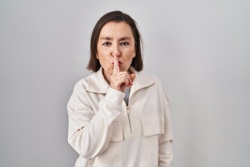 Sticker - Middle age hispanic woman standing over isolated background asking to be quiet with finger on lips. silence and secret concept.