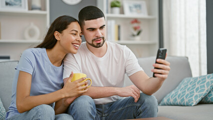 Sticker - Beautiful couple together in love, confidently smiling, texting on smartphone over coffee on living room sofa at home