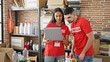 © Krakenimages.com - Man and woman volunteers smiling, working on laptop at charity center, standing together in service for community