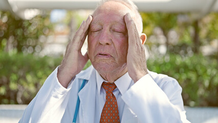 Wall Mural - Senior grey-haired man doctor suffering for headache at park