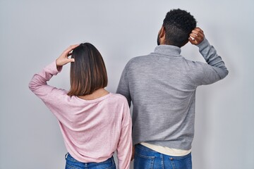 Canvas Print - Young hispanic couple standing together backwards thinking about doubt with hand on head