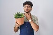 Arab man with beard holding green plant pot touching painful neck, sore throat for flu, clod and infection