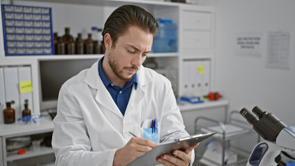 Wall Mural - Young hispanic man scientist writing report sitting at laboratory