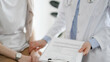 © rogerphoto - Doctor and patient in clinic. Friendly physician examining a young woman with a one hand while keeping a clipboard with medical records in another. Medicine concept
