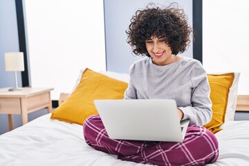 Wall Mural - Young middle east woman using laptop sitting on bed at bedroom