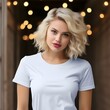 Beautiful Blonde Female model wearing a plain white shirt bella canvas with christmas themed background, bokeh lights, christmas tree 