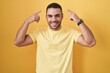 © Krakenimages.com - Young hispanic man standing over yellow background smiling pointing to head with both hands finger, great idea or thought, good memory