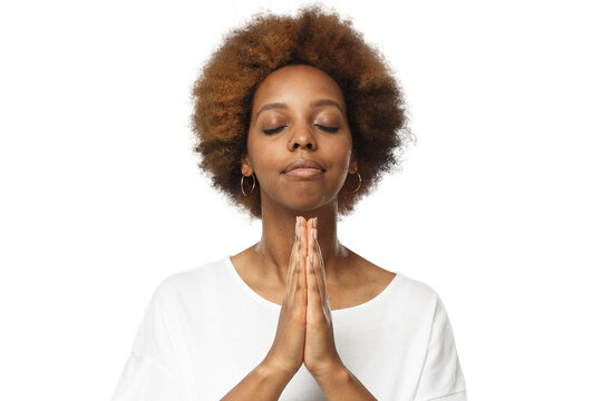Close-up of young african woman putting hands together, praying with closed eyes to find solution