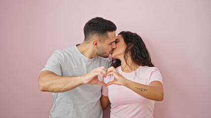 Poster - Man and woman couple doing heart gesture kissing over isolated pink background