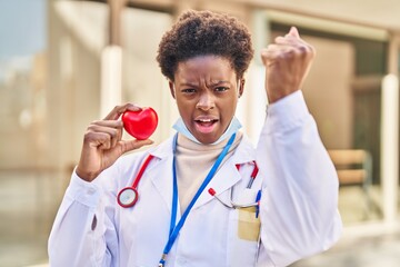 Sticker - African american woman wearing doctor uniform holding heart annoyed and frustrated shouting with anger, yelling crazy with anger and hand raised