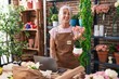 © Krakenimages.com - Middle age grey-haired woman florist using laptop holding plant at florist