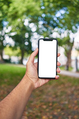 Man holding smartphone showing white blank screen at park