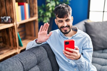 Sticker - Young hispanic man having video call sitting on sofa at home