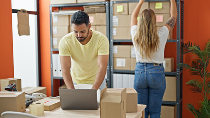 Wall Mural - Man and woman ecommerce business workers using laptop holding package of shelving at office