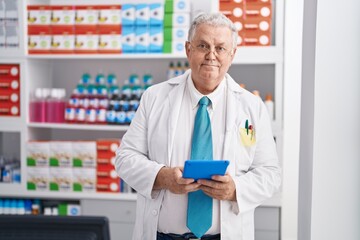 Wall Mural - Middle age grey-haired man pharmacist using touchpad working at pharmacy