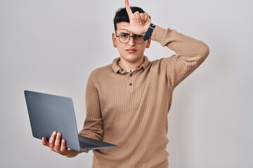 Canvas Print - Non binary person using computer laptop making fun of people with fingers on forehead doing loser gesture mocking and insulting.