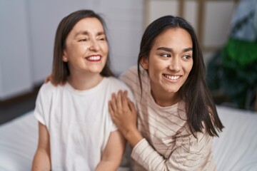 Wall Mural - Two women mother and daughter hugging each other sitting on bed at bedroom