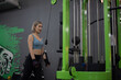 Strong young Asian woman exercising with triceps rope pulldown in a fitness club, doing exercises in gym