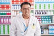 Chinese young man working at pharmacy drugstore winking looking at the camera with sexy expression, cheerful and happy face.