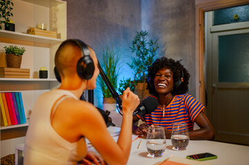 Wall Mural - Two cheerful girls are sitting at home recording studio and making a podcast.