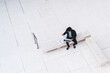 © BullRun - Freelance male siting on bench checking documents while using laptop in marble yard on street