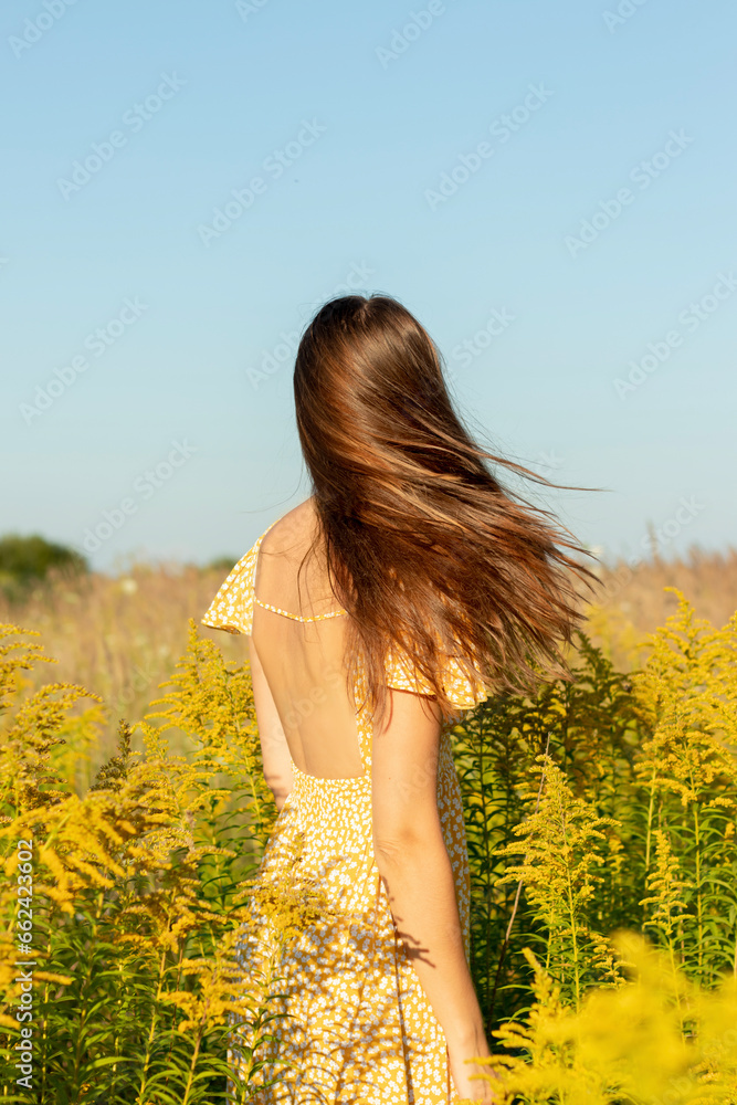 Young beautiful woman in yellow dress closeup with yellow field flowers ...