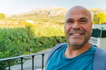 Wall Mural - Happy man takes a selfie outdoors, landscape on background. 