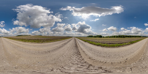 Wall Mural - 360 hdri panorama on wet gravel road with marks from car or tractor tires with clouds on blue sky in
