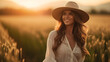 © Design Council - Portrait of a female farmer wearing overalls and a straw hat, standing in the middle of a green wheat field during sunrise Agriculture