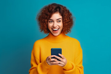 funny cheerful woman in yellow sweater with a phone in her hands. Smiling young woman looking at her phone and smiling at the good news.