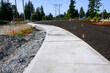 New residential community construction site, freshly poured concrete sidewalk and landscaping installation
