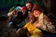 © CarlosBarquero - Group of cheerful multi-ethnic friends pose hugging and smiling for outdoor selfie phone. Happy young adults gathered at campsite on winter night. Positive social relations on camping vacation.