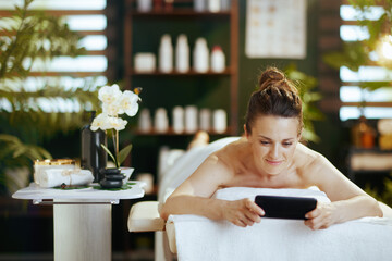 Wall Mural - woman in spa salon using smartphone and laying on massage table